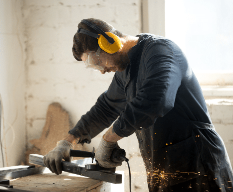 Man sawing wood while using hearing protection